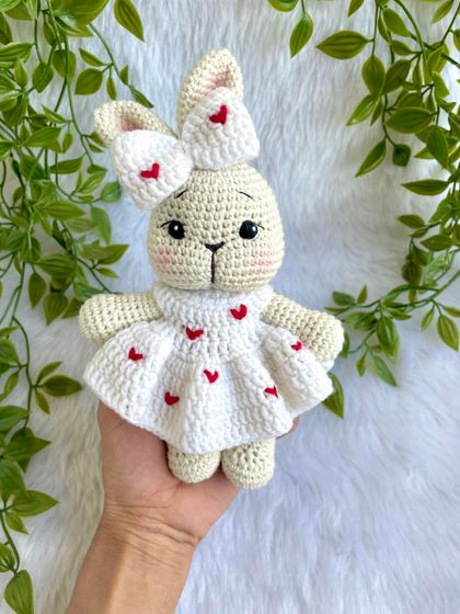 This sweet bunny is dressed in a white frock adorned with little red hearts. The matching bow on her ear makes her extra cute. A perfect gift for Valentine's Day or for someone you love.