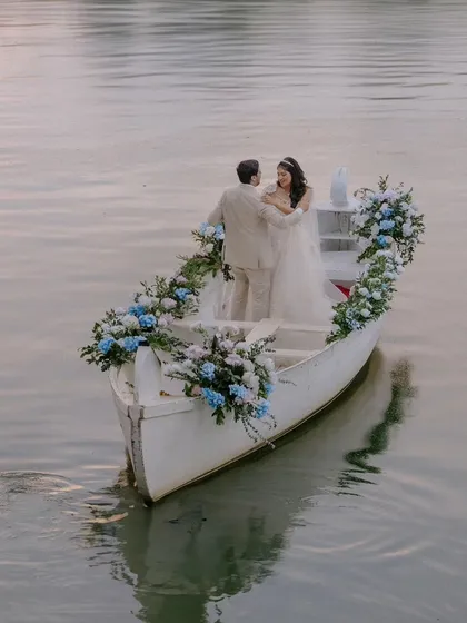 We believe in creating fairy-tale moments that feel both grand and intimate. This serene shot of Sudhira and Prajwal in a flower-adorned boat is a perfect example of how we craft unforgettable, romantic experiences as part of your wedding story.