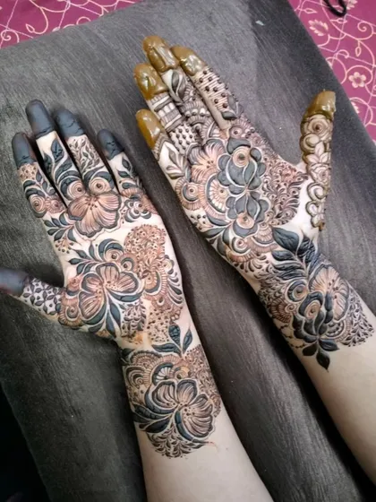 Two hands, two complementary designs for a bride and her siders. One hand features bold, shaded florals while the other has more delicate, spaced-out motifs, showing how I can create a unified look for the whole bridal party.