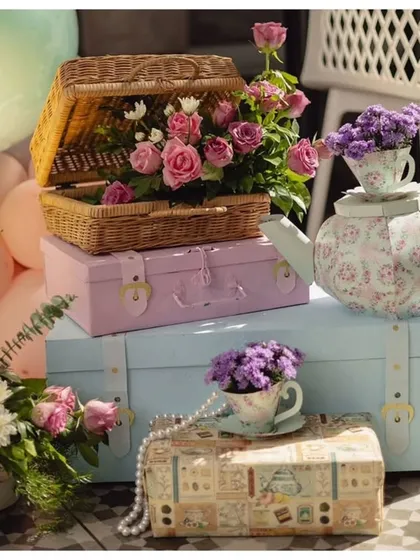 Themed props for a tea party celebration. I used vintage-style suitcases, a floral teapot, and wicker baskets filled with roses to create a charming and whimsical display.