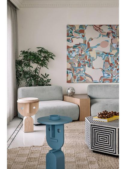 A detail of the living room, showcasing the playful, face-designed side tables and the rich textures of the furniture and rug.