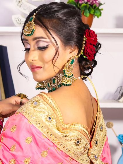 A side profile showcasing the elegant bridal reception hairstyle. The soft updo is adorned with red roses, adding a touch of traditional romance to her modern look.