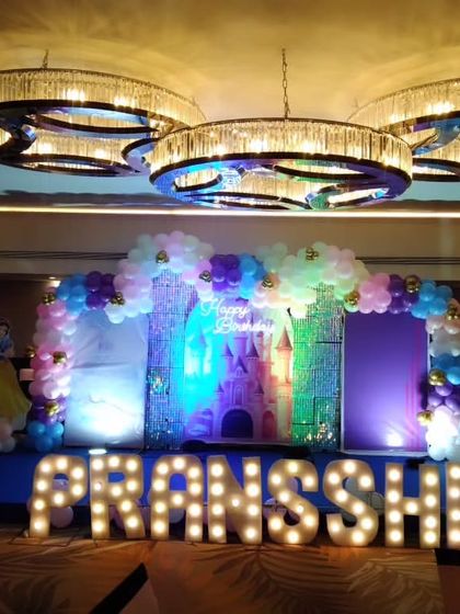 A princess castle-themed stage for a first birthday, with marquee letters spelling out the name "PRANSSHI" and beautiful lighting.