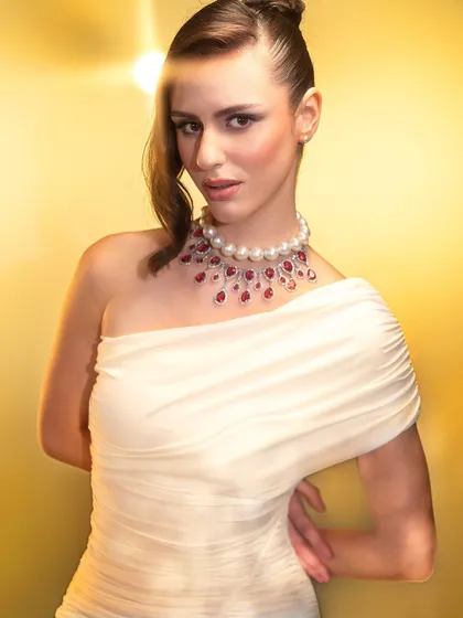 A classic beauty portrait with a modern twist. The lighting is soft and flattering, while the pop of the lens flare and the elegant pearl and ruby necklace add a touch of glamour.