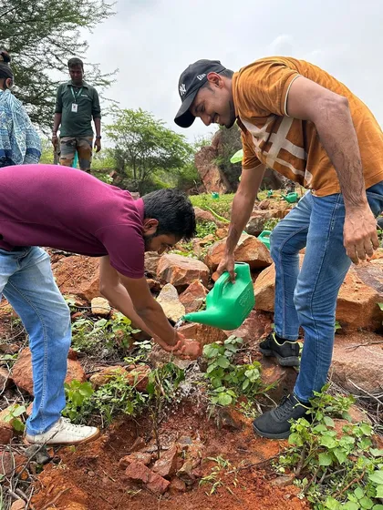 Two volunteers from Beumer Group work together to water a newly planted sapling on the rocky slopes of Aravali Nagar Van, braving the heat to make a difference.
