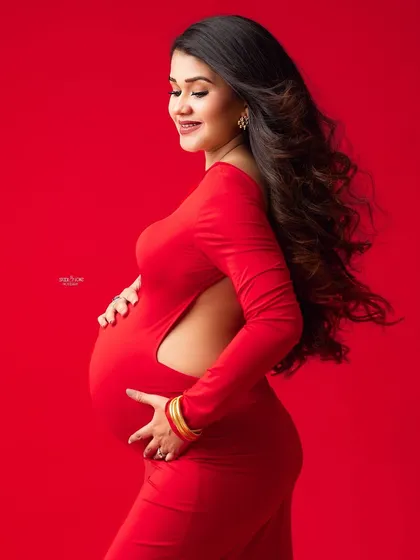 A close-up to capture the pure joy and radiance of this mamma-to-be in a striking red dress.