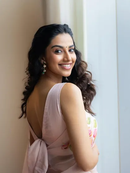 A lovely over-the-shoulder shot from the pink floral saree look. This angle highlights the beautiful back detail of the blouse and the model's soft, natural hair and makeup.