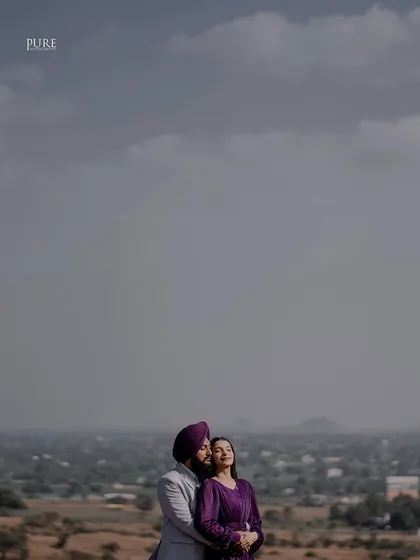 A stunning landscape portrait with the couple as a small, intimate part of a vast, beautiful view. This shot emphasizes the epic scale of their love against a dramatic sky.