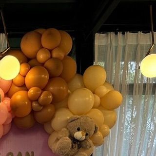 Another detail shot of the pastel balloon decor, with a teddy bear peeking out from behind a cluster of orange and yellow balloons.