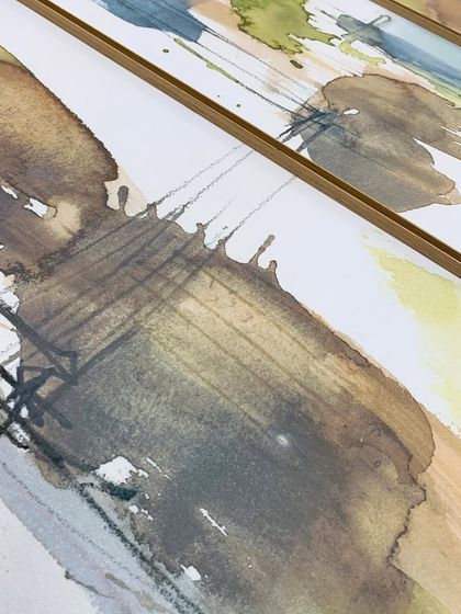 A detailed view of the "Dusty Splash" abstract artwork, showing the subtle texture of the paper and the delicate lines within the watercolor, all protected behind glass in a minimal metal frame.