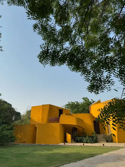 Framed by the leaves of a neem tree, the building feels like a natural extension of the surrounding landscape.