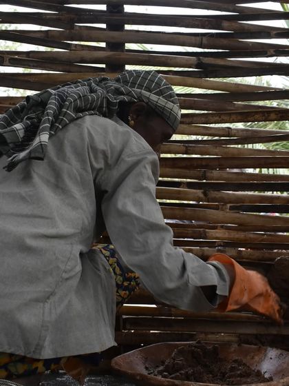 A mason carefully applies mud to a bamboo wattle frame. This work combines traditional materials with a mission to empower women in the construction industry.