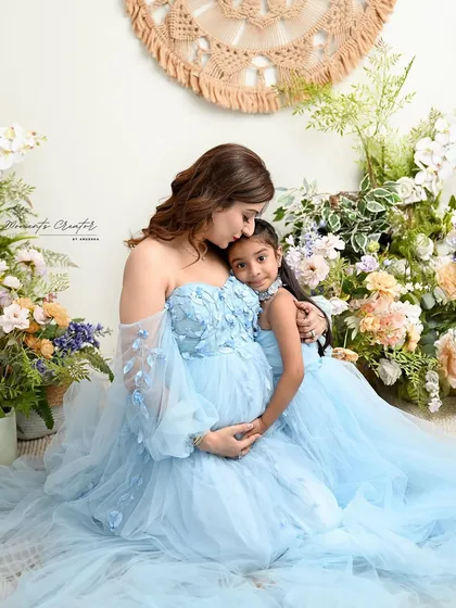A mother's loving embrace. This tender moment between mother and daughter, both in matching blue gowns, is a perfect example of the emotional storytelling I aim for.