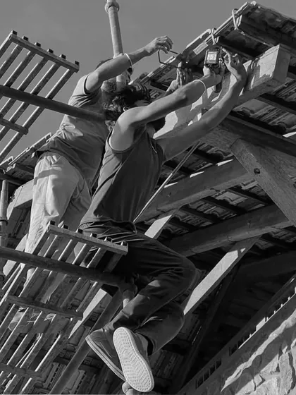 Perched on scaffolding, our team works on the details of a sloping roof against a stone wall. This is where design meets execution, rooted in nature and built by hand.