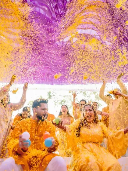 A spectacular 'phoolon ki holi' where guests shower the couple with a vibrant explosion of yellow and purple flower petals.