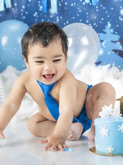 Crawling towards the cake! This little boy is ready to dig into his first birthday treat in this winter wonderland setup.