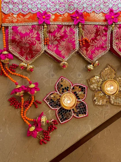 I love playing with vibrant colors in my bandhanwars. This piece combines a hot pink brocade fabric with orange beadwork and floral details, creating a festive and welcoming entrance for your home.