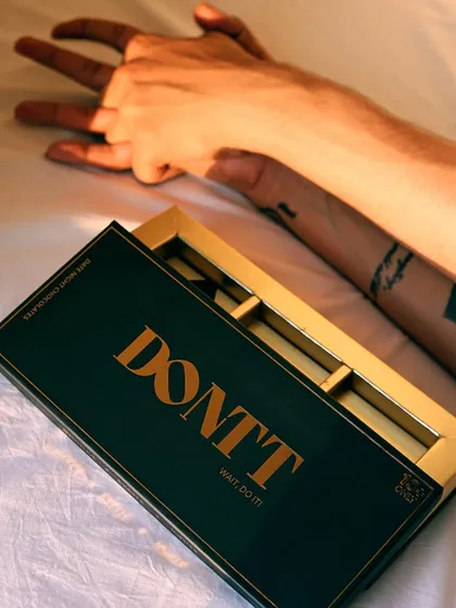 An artistic, top-down shot that combines the product with a human element. The focus on the hands and the empty box tells a story of indulgence.