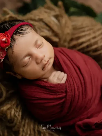 Nestled in a rustic basket, this little one is swaddled in a deep red wrap. The natural textures of the jute and wood create a warm, organic feel.