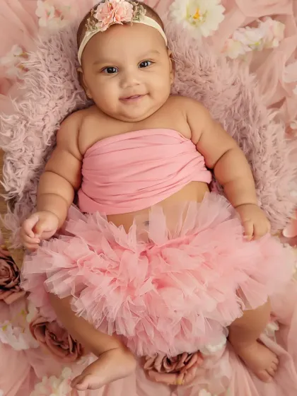 This little girl's chubby rolls and happy expression are the stars of her four-month photoshoot.