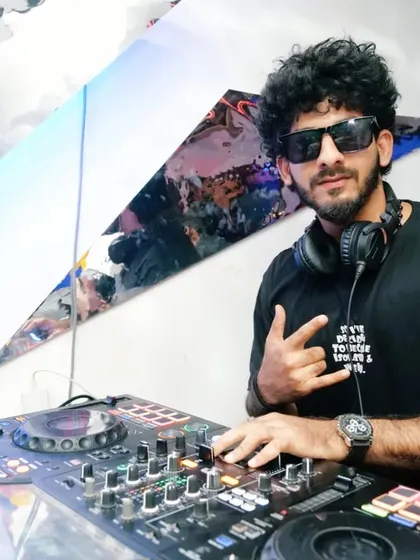 Posing with a rock-on sign from behind the decks. I bring confidence and a cool attitude to every performance.