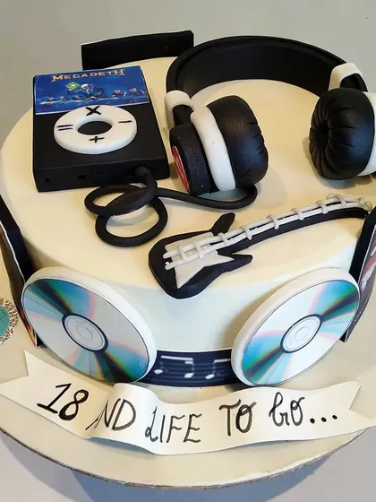 A cake celebrating a love for music. This design is topped with an edible retro iPod, headphones, a guitar, and CDs, perfect for an 18th birthday.