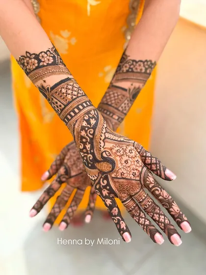 A striking bridal mehendi design with bold peacock motifs. The contrast between the dark, filled-in peacocks and the delicate surrounding patterns creates a very impactful look.