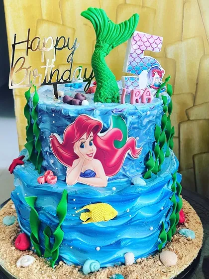 Dive into an underwater adventure with a mermaid-themed cake. This two-tiered creation uses shades of blue buttercream to mimic ocean waves and is decorated with handmade fondant sea creatures and an Ariel topper, all built around my rich chocolate cake.