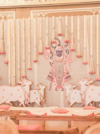 An alternate stage setup for the Pichwai theme, featuring motifs of Shrinathji and holy cows, framed by curtains of fresh jasmine flowers (gajras).