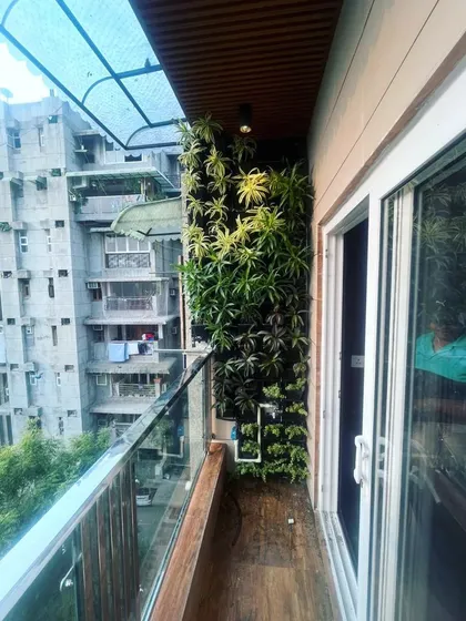 A wider view of the natural vertical garden on a city balcony, showing how it fits seamlessly next to the sliding glass door, bringing the outdoors in.