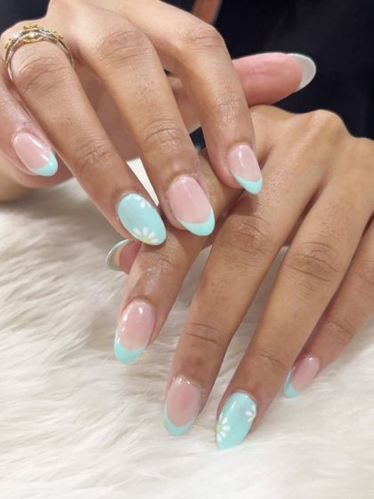 A sweet and charming design. This look features a pastel mint green French tip with accent nails adorned with tiny, hand-painted daisies.