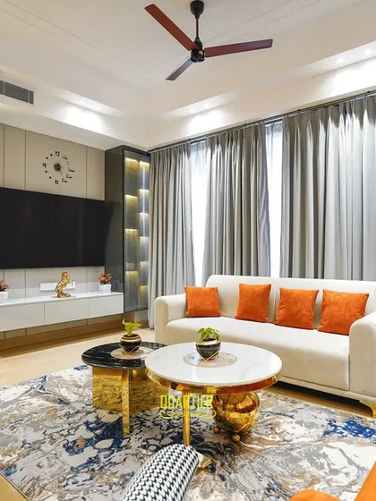 Bold colors and textures define this living room at Apex D’Rio, Indirapuram. I paired a vibrant orange sofa with houndstooth-patterned armchairs and a striking abstract rug to create a space that is full of personality and modern flair.