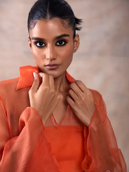 This look for Akashi Clothing features a warm, monochromatic orange outfit. The makeup is kept bronzed and sun-kissed, with a soft smokey eye to add definition.
