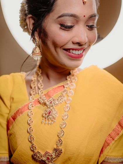 A joyful and radiant portrait of the bride, her smile lighting up the frame. The warm tones and ring light create a flattering glow.
