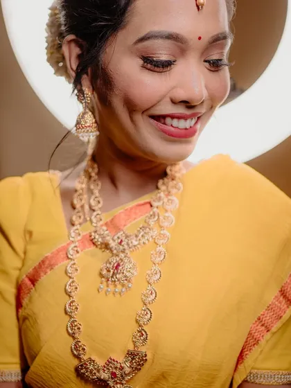 A joyful and radiant portrait of the bride, her smile lighting up the frame. The warm tones and ring light create a flattering glow.
