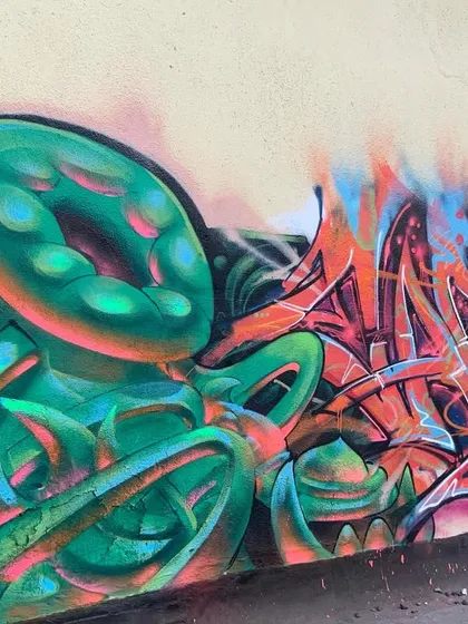A full view of the 'bijli flow' piece, showing the contrast between the cool green bio-mechanical forms and the hot orange and pink lettering.
