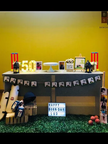 We hit it for a six with this custom cricket theme for a state cricketer's 50th birthday. The decor features a personalized 'Happy Born Day' lightbox, marquee numbers, and authentic cricket gear like pads, a helmet, and a custom photo bat to celebrate his passion.