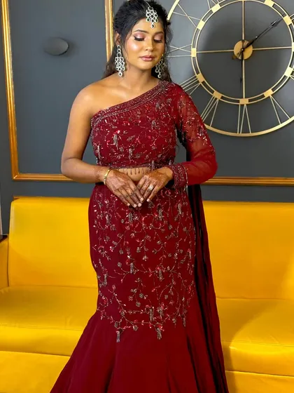 A full-length shot showing how the complete look comes together. The warm, glowing makeup perfectly complements her deep red, one-shoulder gown, creating a cohesive and stunning appearance.