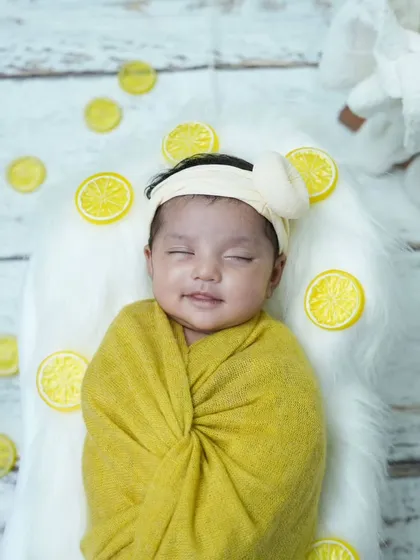 A sleepy smile from our little lemon drop. Wrapped in a cheerful yellow swaddle, this newborn is dreaming sweet dreams.