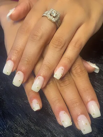 A milky white ombré manicure with tiny gold bead accents.