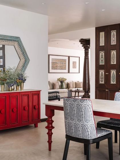 A bold red cabinet and a dining table with turned legs add a pop of color and traditional craftsmanship to the dining area.