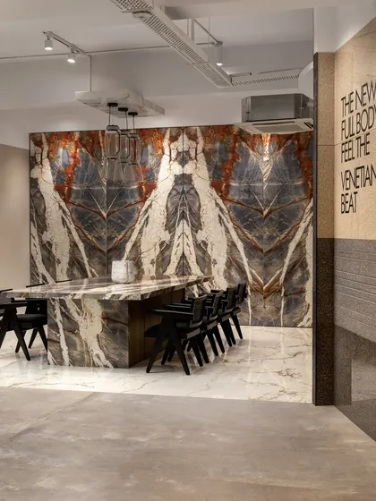 Luxury redefined at an Italian tile showroom in Mumbai. Here, extra-large tiles mimicking luxurious marble adorn the walls and a communal table, transforming the ordinary into the extraordinary.