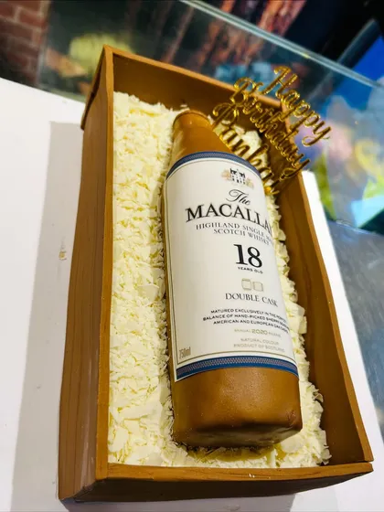This hyper-realistic Macallan whisky bottle cake looks just like the real thing, nestled in a box of edible white chocolate shavings. It was the perfect surprise for a connoisseur's birthday, proving that cakes for grown-ups can be sophisticated and fun.