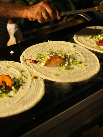 This is my Peri Peri Dosa being made on the griddle. It's a vibrant and flavourful creation, loaded with fresh veggies, spicy sauces, and a generous topping of cheese for a perfect fusion of flavours.