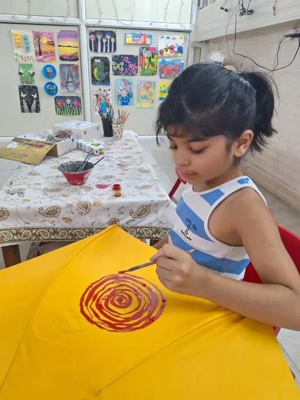 A quiet moment of concentration as a young participant paints a vibrant design on her yellow umbrella. My workshops are a space for both fun and focus.