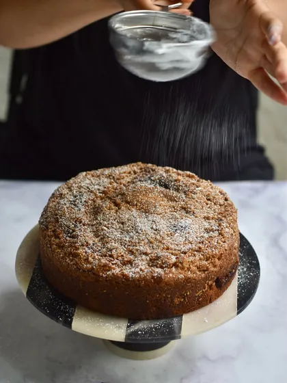 A slice of our Plum & Almond Crumble Cake, dusted with powdered sugar.