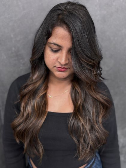 A client enjoying her new caramel balayage. The soft waves and subtle color lift create a beautiful, low-maintenance style.