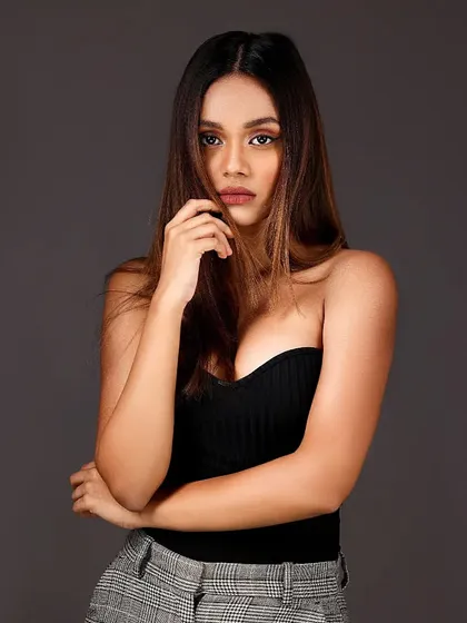 A moody and alluring headshot of a model against a grey background, with her hair partially covering her face.