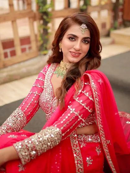 This look is pure couture glamour, perfect for an engagement or sangeet. The makeup features a defined smokey eye and a warm nude lip, creating a powerful yet graceful look that harmonizes with the vibrant pink of her embellished lehenga. It’s all about creating a memorable, high-fashion moment.