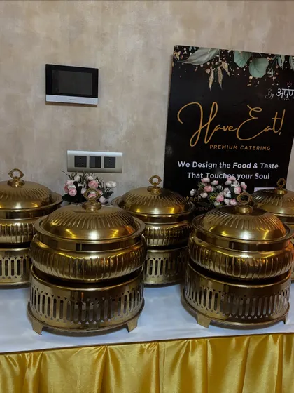 Our signature gold chafing dishes ready for a house party, placed next to our service banner.